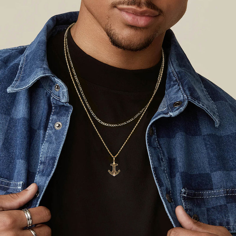 Man wearing a gold anchor necklace with a denim jacket and black shirt.