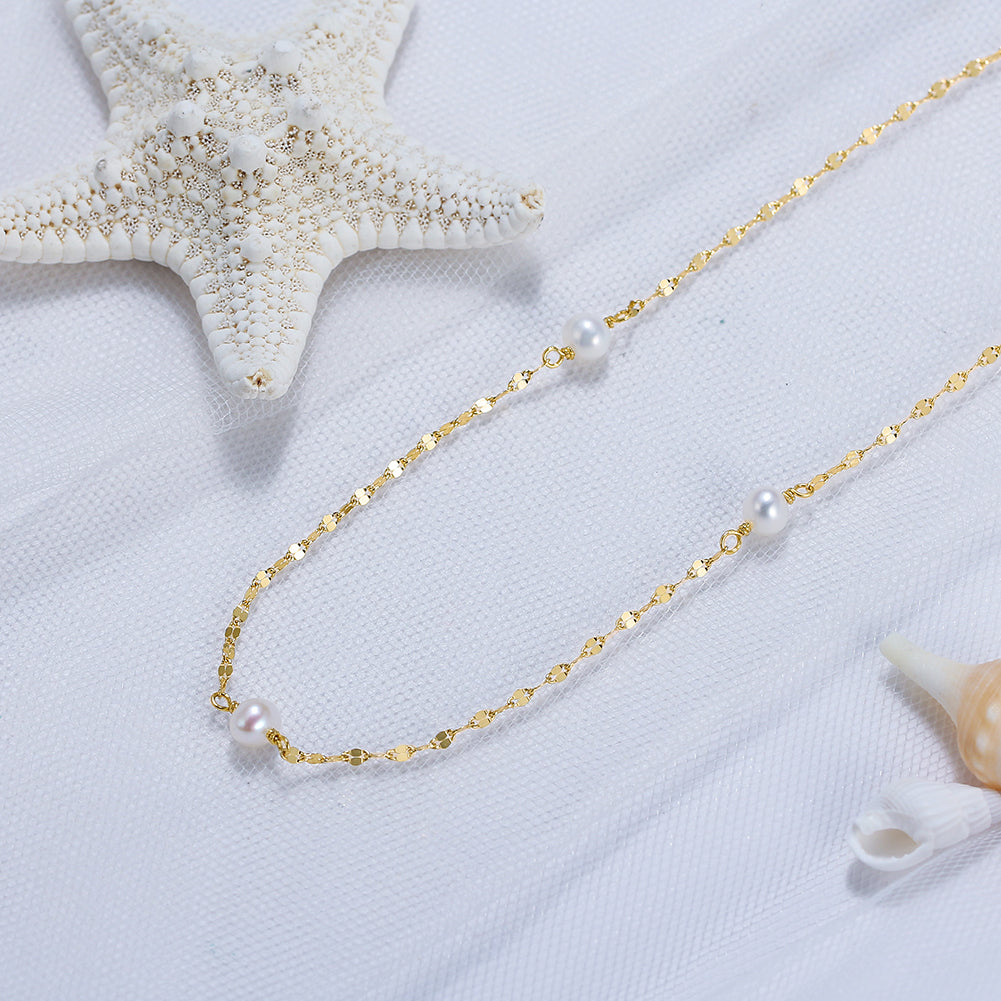 Gold necklace with pearls on a white background with starfish and shell decorations