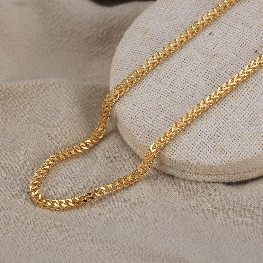Gold chain on a textured beige surface