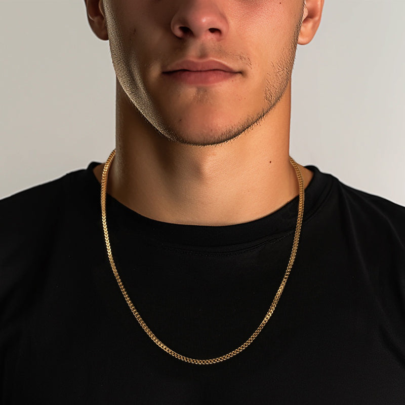 Man wearing a gold chain necklace against a neutral background