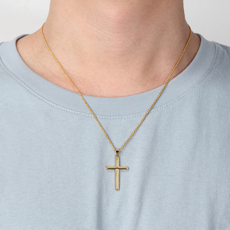 Gold cross necklace on a person wearing a light blue shirt