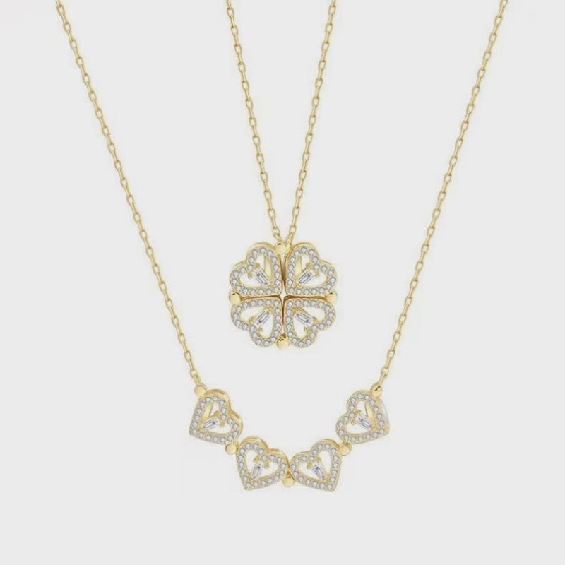 Gold necklace with heart-shaped pendants on a light gray background