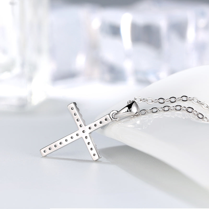 Silver cross necklace on a white dish with a blurred background