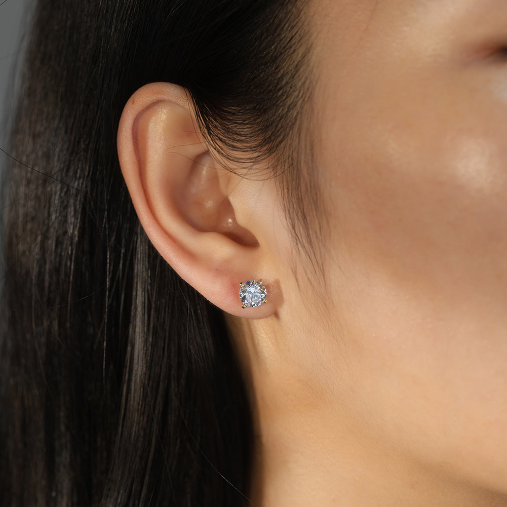 Close-up of an ear wearing a diamond CZ stud earring with dark hair and blurred background