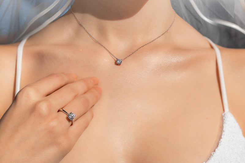 Close-up of a diamond CZ necklace and ring on a person's chest