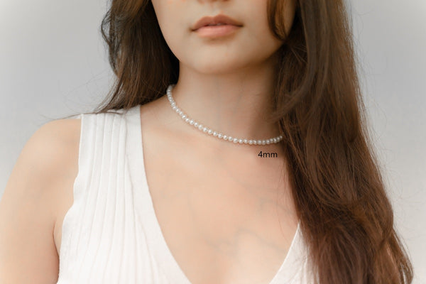 A woman wearing a white dress and a choker 4 mm pearl necklace