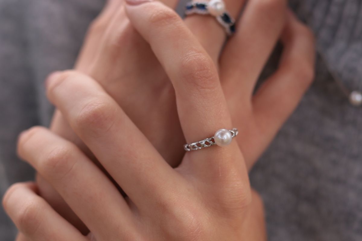 finger wearing silver and pearl ring