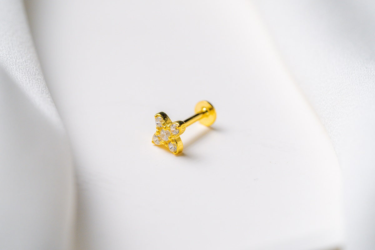 A gold earring in a star shape featuring cubic zirconias on a white background