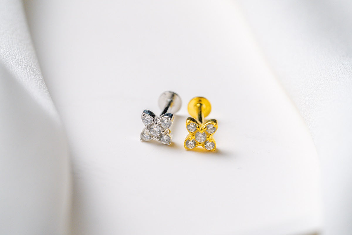 A silver and a gold earring in a star shape featuring cubic zirconias on a white background