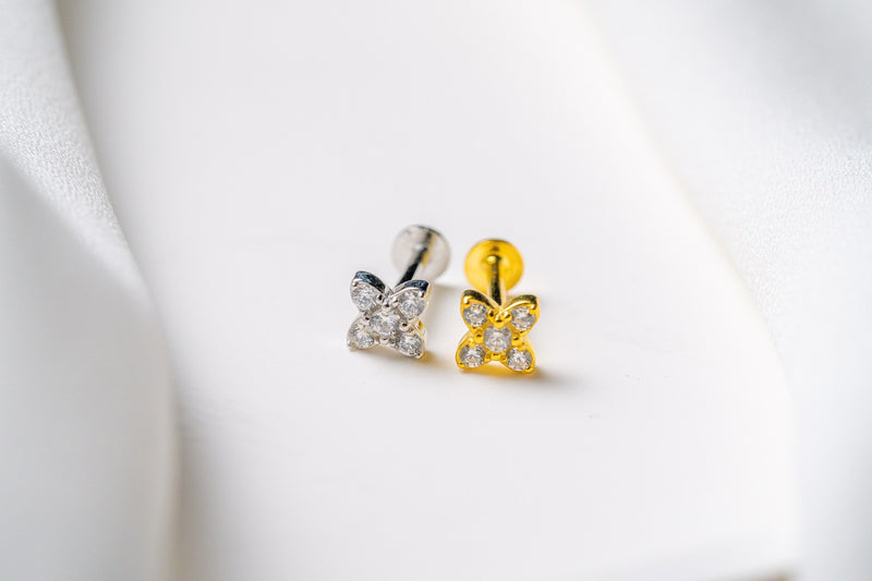A silver and a gold earring in a star shape featuring cubic zirconias on a white background