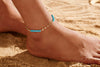 Close up of a foot wearing a gold anklet with light blue colored beads