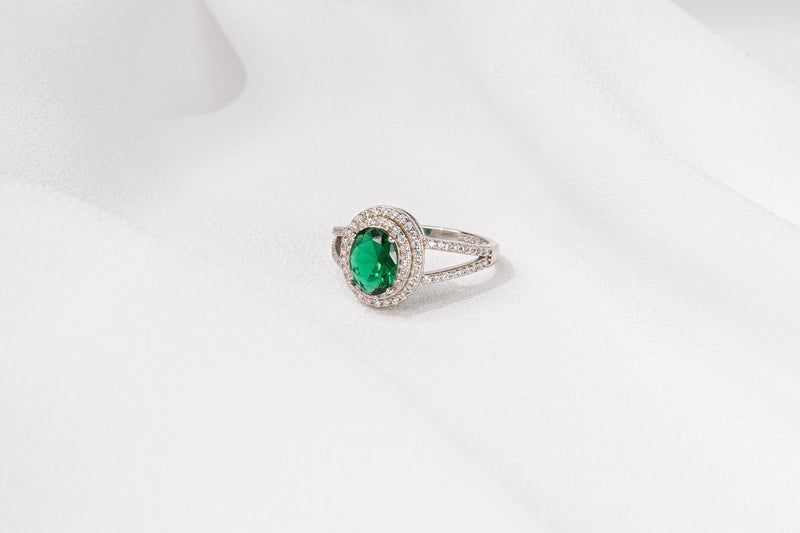 Silver ring featuring a vivid green gem stone and cubic zirconias on a white background