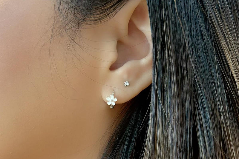 Close-up of an ear wearing a floral earring with a blurred background