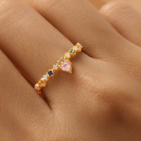 Gold ring with colorful gemstones on a person's finger