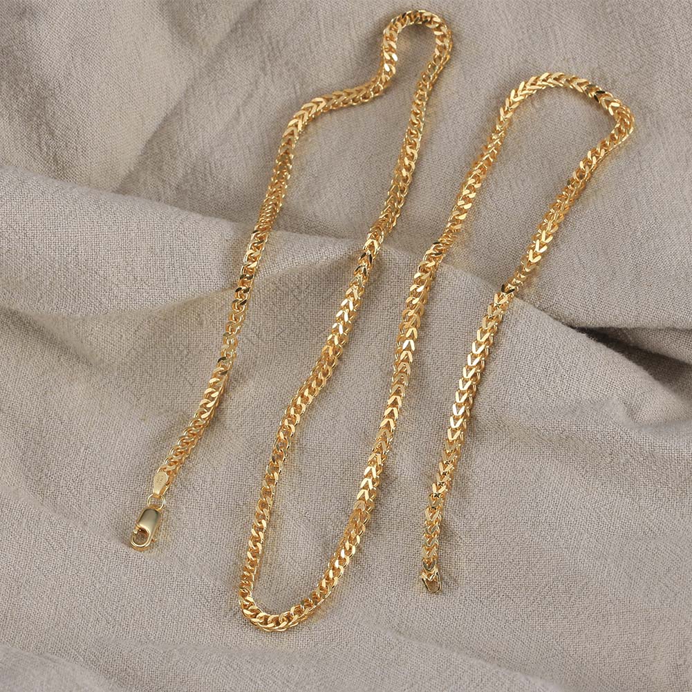 Two gold chains on a textured beige surface