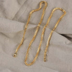 Load image into Gallery viewer, Two gold chains on a textured beige surface
