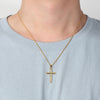 Gold cross necklace on a person wearing a light blue shirt