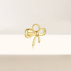 Gold bow-shaped earring on a light beige background