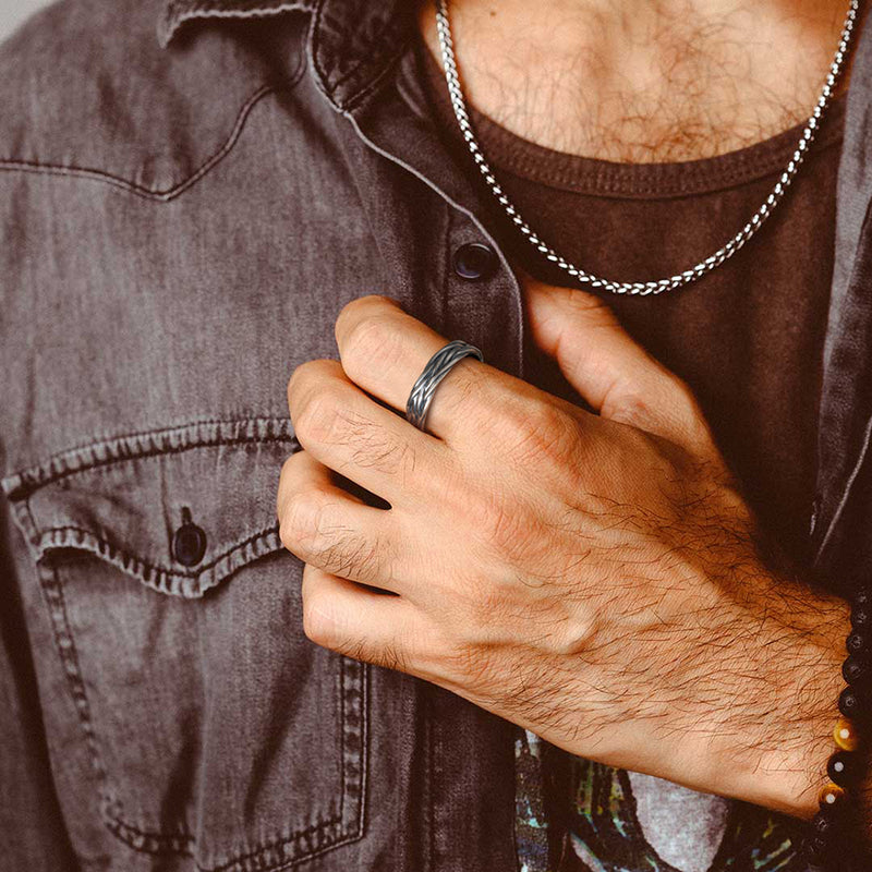 Man wearing a denim jacket and brown shirt with a focus on their silver ring 