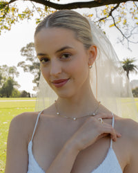 Bride wearing white wedding dress and veil with pearl earrings and necklace 