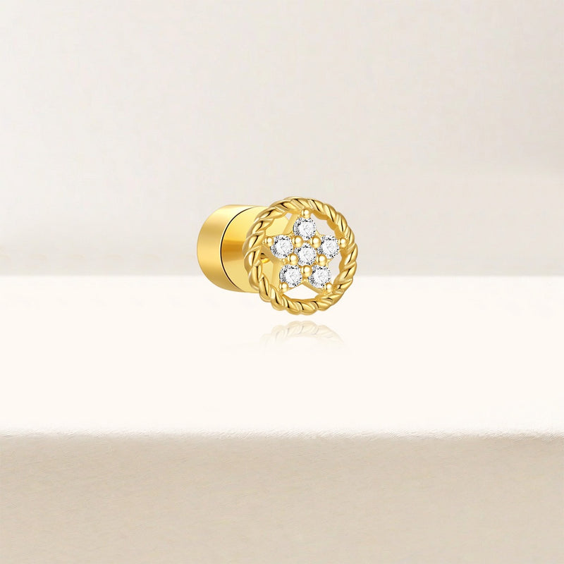 Gold stud earring with floral design on a beige background