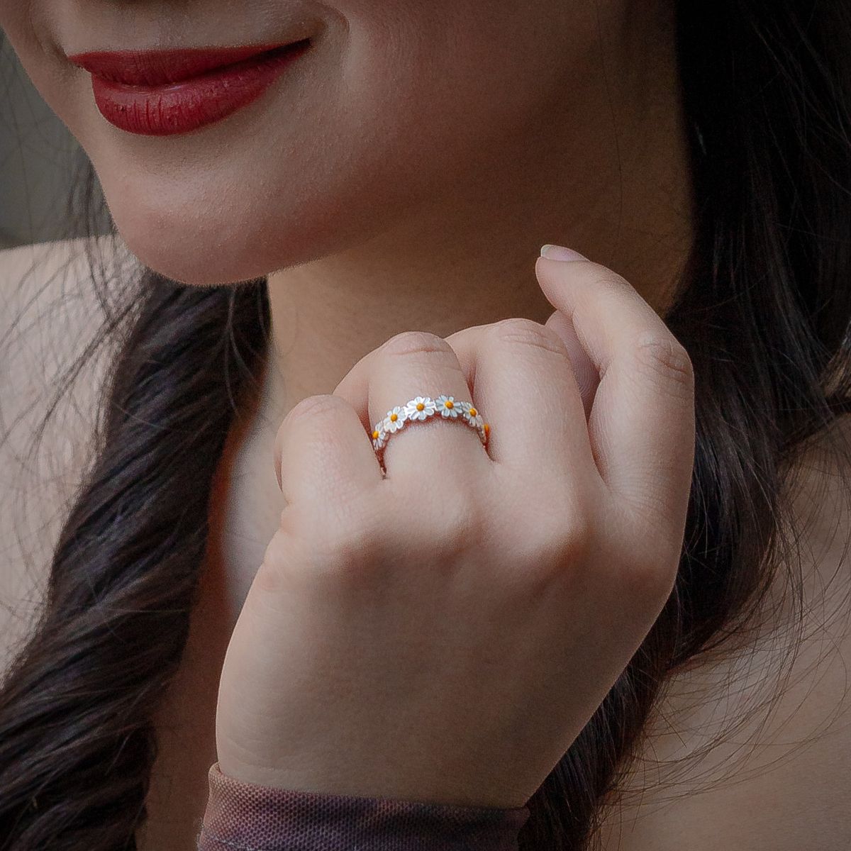 Close-up of a woman's hand wearing a floral Daisy rng with a blurred background