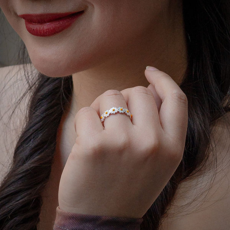 Close-up of a woman's hand wearing a floral Daisy rng with a blurred background