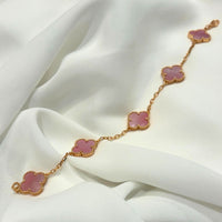 Gold bracelet with pink floral links on a white fabric background