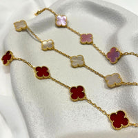 Gold necklace with clover-shaped pendants on a white fabric background
