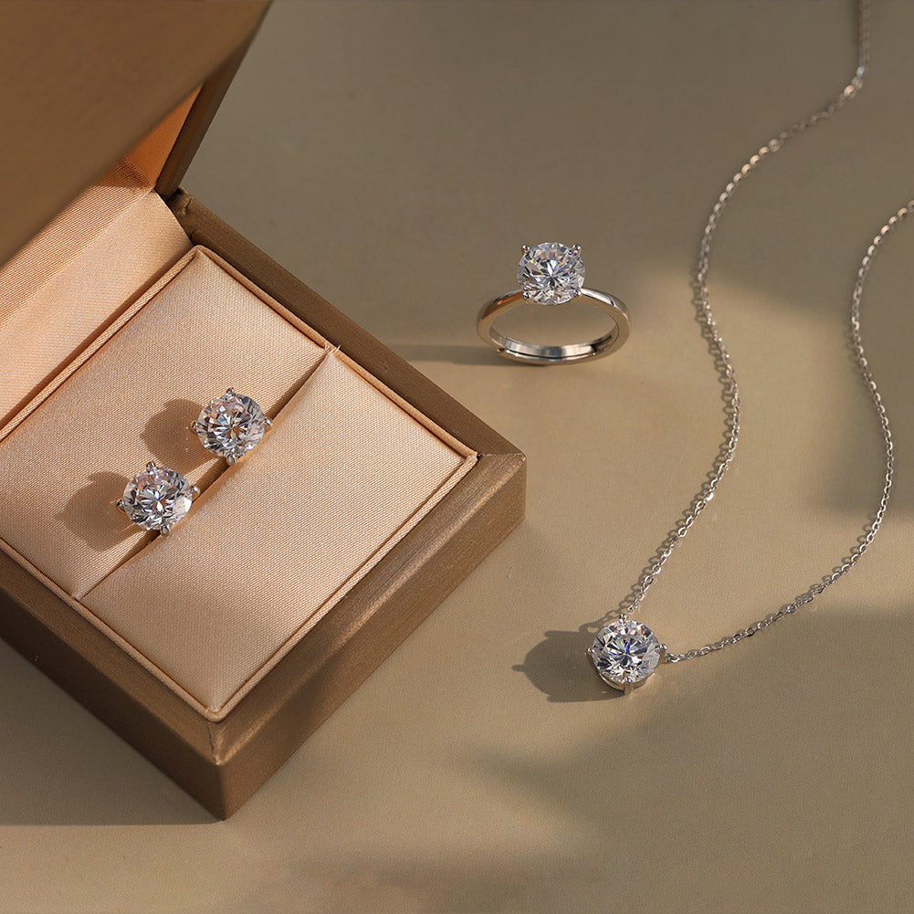 Diamond jewelry set including ring, earrings, and necklace on a beige background