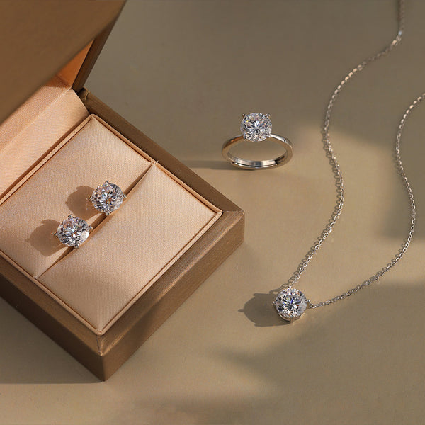 Diamond jewelry set including ring, earrings, and necklace on a beige background