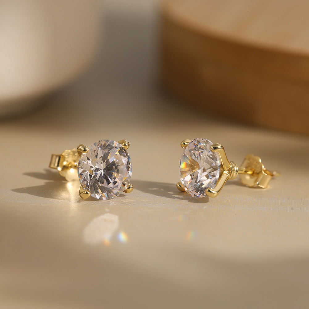 Gold stud earrings with Diamond CZ on a beige surface