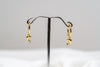 A pair of gold vermeil hoop earrings with a dolphin design dangling from the hoops, displayed against a white background.