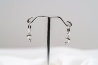 A pair of Silver hoop earrings with a dolphin design dangling from the hoops, displayed against a white background.