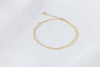 A gold-colored double-layered anklet, displayed on a white background.