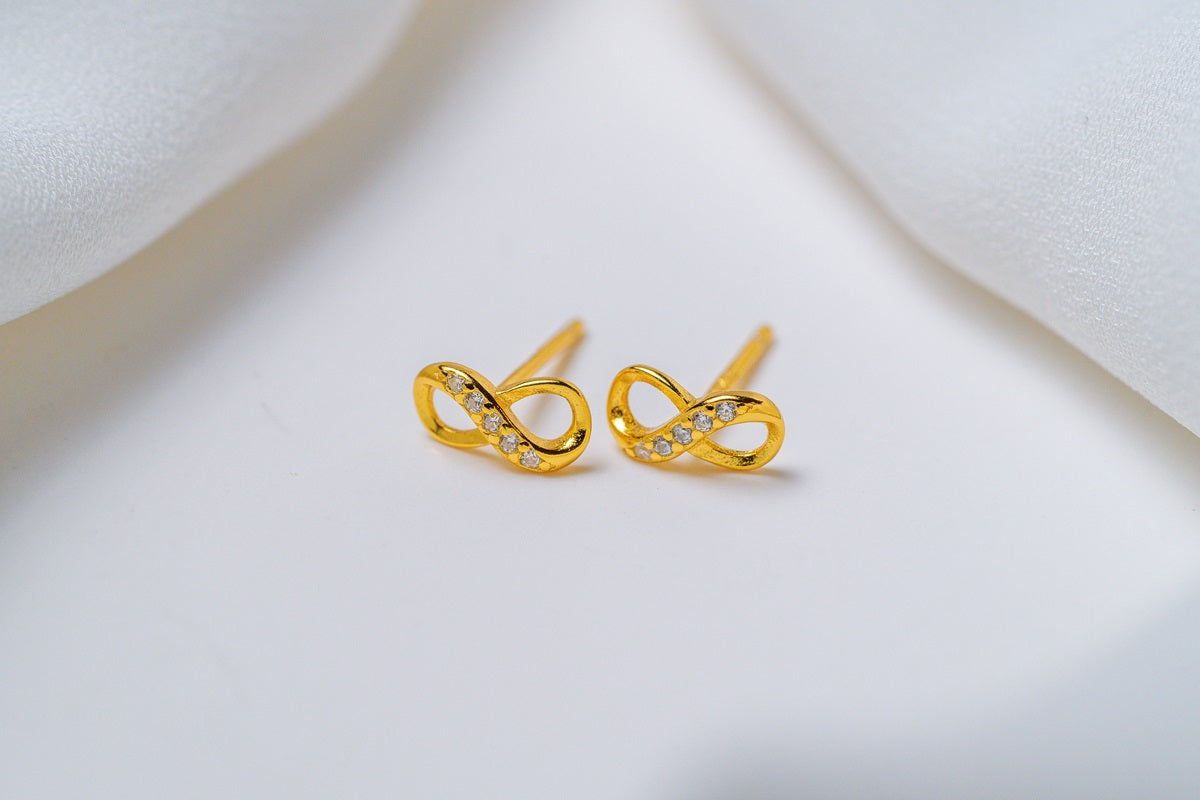 A pair of stud earrings with a butterfly back design, made of sterling silver, displayed on a white fabric surface.