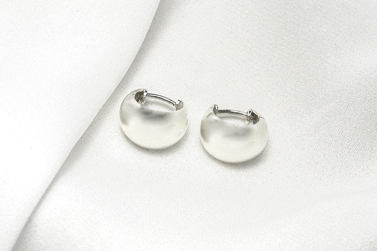 A pair of sterling silver hoop earrings displayed on a white fabric surface.