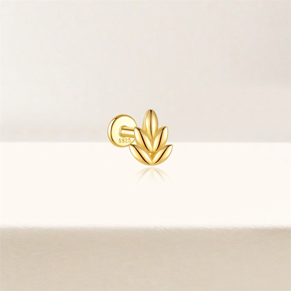 Gold leaf-shaped earring on a light beige background