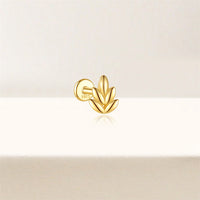 Gold leaf-shaped earring on a light beige background