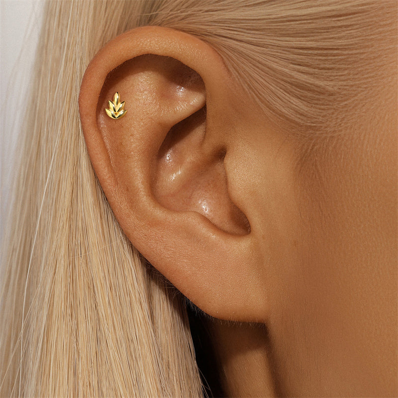 Close-up of an ear wearing a gold earring with blonde hair.