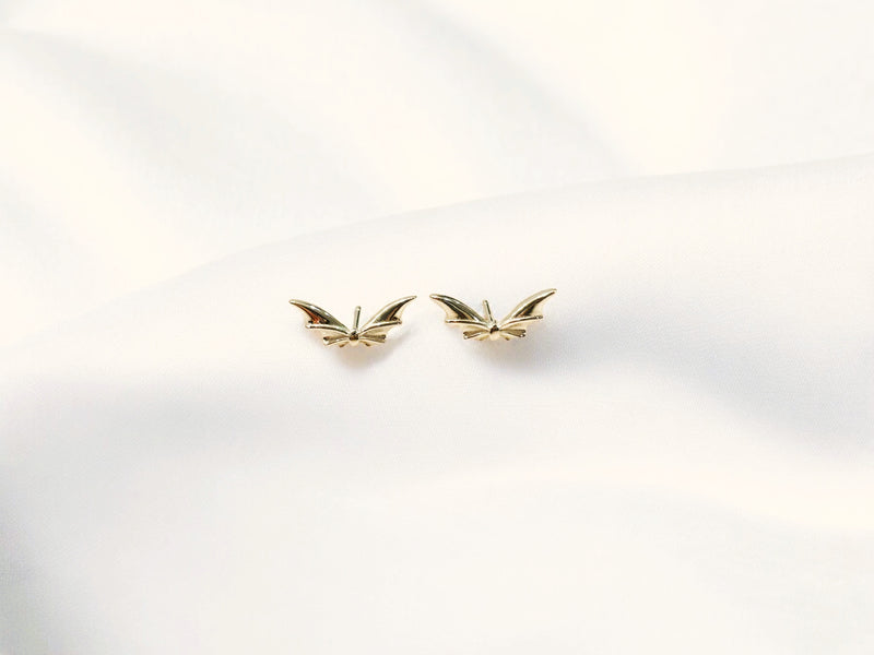 flying bat shaped earrings on a white background