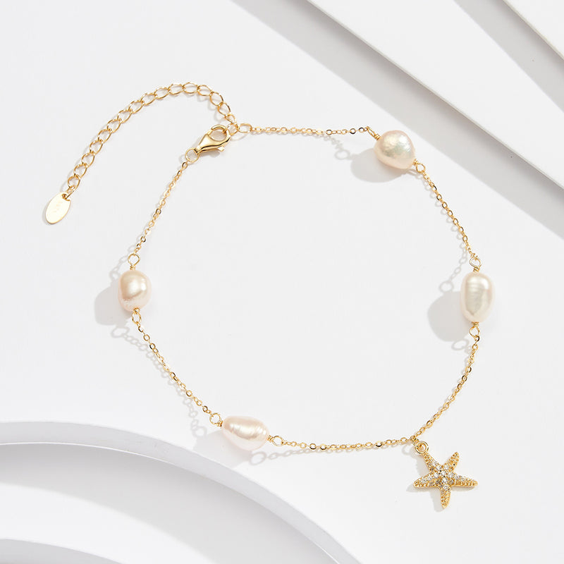 A gold-colored sterling silver anklet with white pearl beads and a star-shaped charm, displayed on a white background.