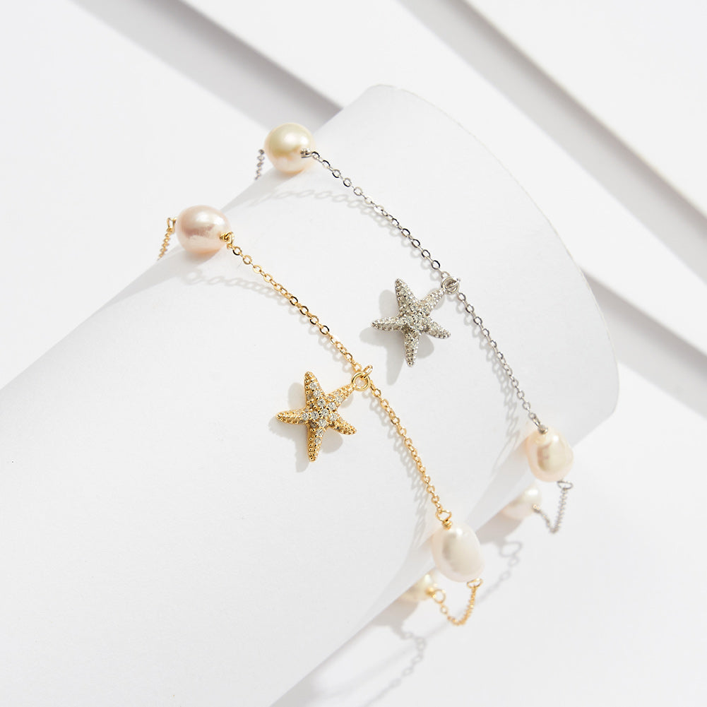 A gold and a silver anklet on a display. Featureing pearls and a starfish pendant.