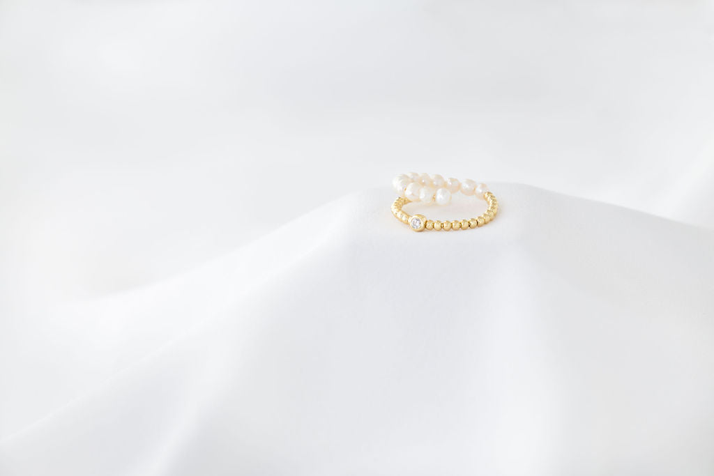 An image of a gold vermeil ring with white pearl accents on a white background.