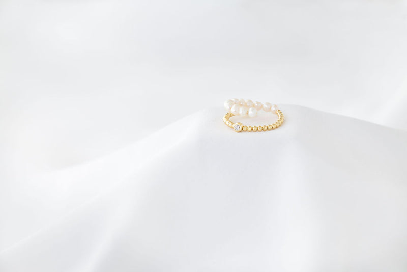 An image of a gold vermeil ring with white pearl accents on a white background.