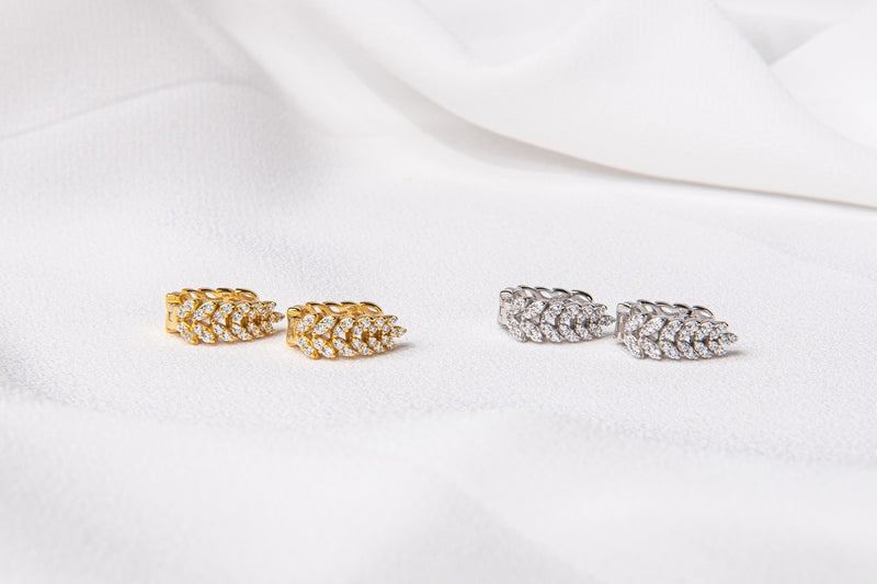 A pair of gold vermeil and sterling silver hoop earrings with diamond cubic zirconia patterns, displayed on a white fabric surface.
