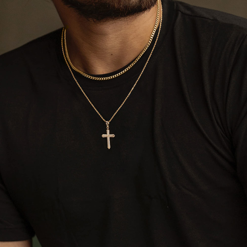 Man wearing a black tshirt with a gold chain and cross pendant necklace.