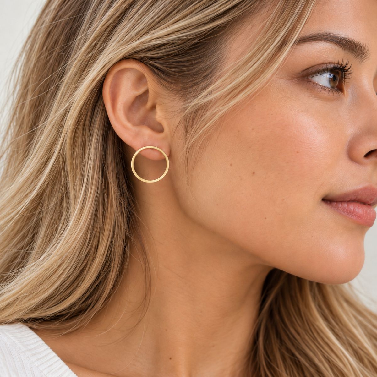 Model with dyed hair wearing gold plated hoops