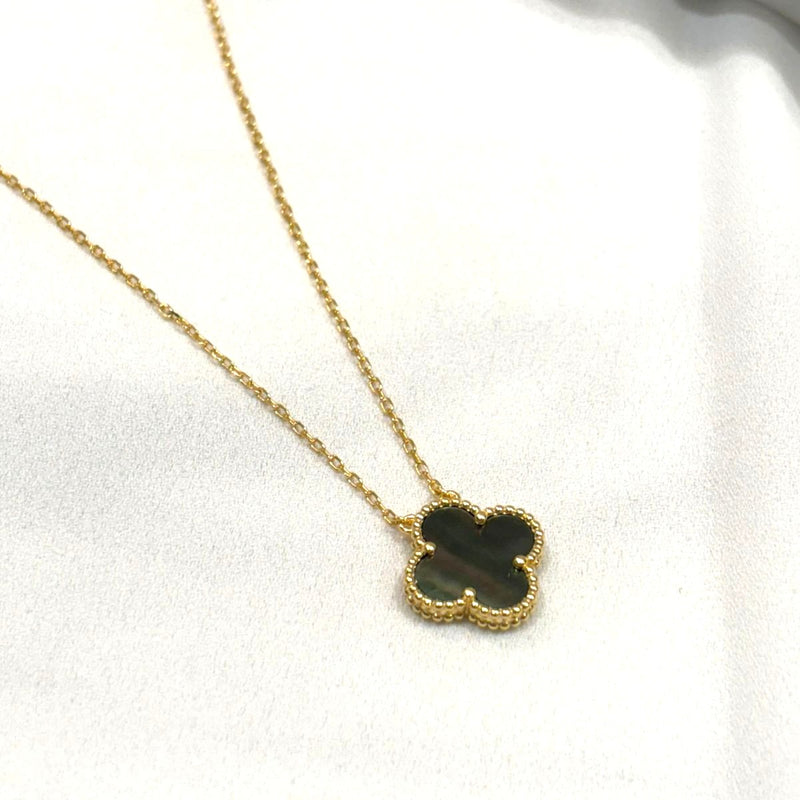 Gold necklace with a clover-shaped pendant on a white background