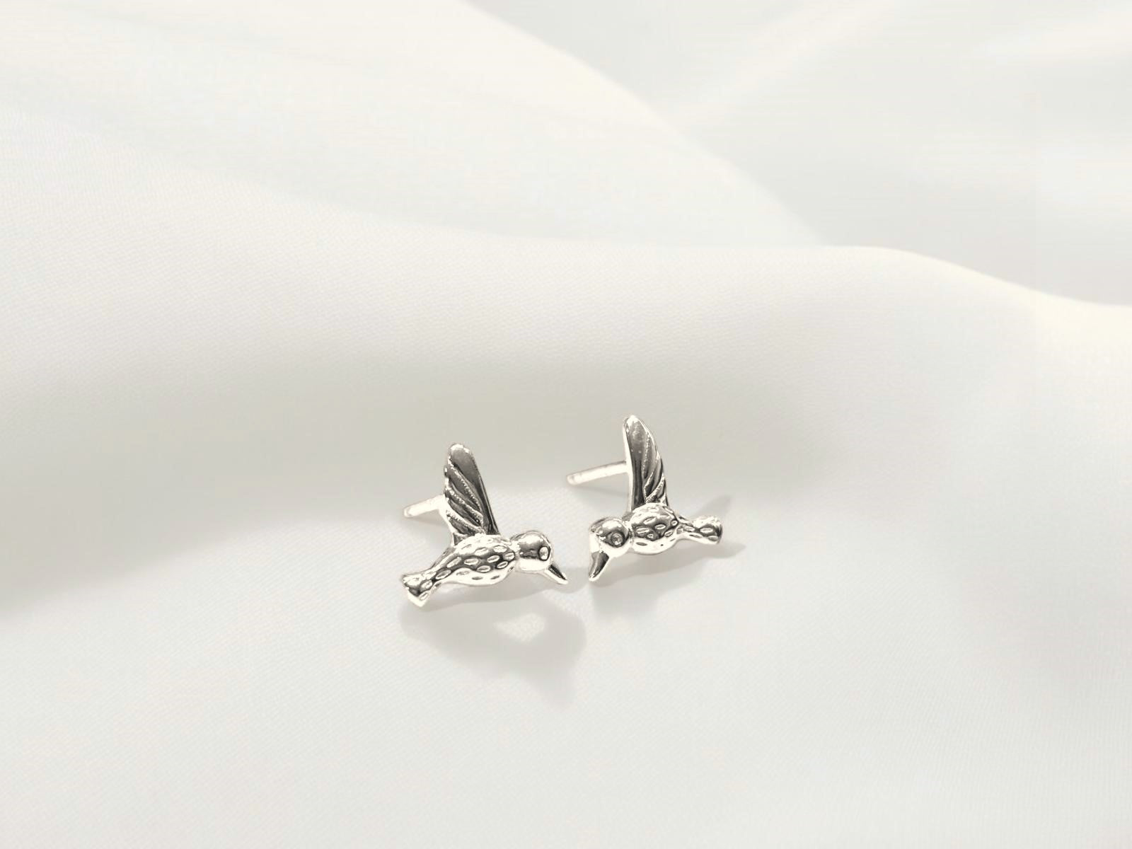 A pair of sterling silver stud earrings with a butterfly back, displayed against a white fluffy background.
